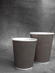 2 sizes of Plastic and Paper coffee cup on grey Table