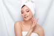 © veles_studio - attractive woman in bath towel applying cream on her face isolated on white