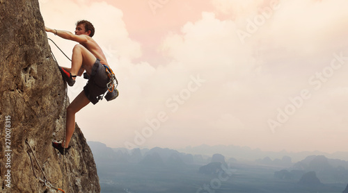 Cuadros en Lienzo Young man climbing on a limestone wall with wide valley on the background