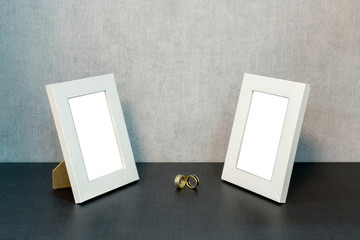 two empty wooden white photo frames on the shelf, in the middle gold rings, wedding concept, mock-up