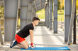 © Olha - Young man training yoga outdoors. Sporty guy makes stretching exercise on a blue yoga mat, on the sports ground.