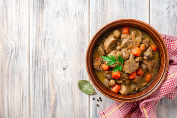 Wall Mural - Turkey meat stew with mushrooms and vegetables in ceramic bowl on wooden table. Top view. Copy space.