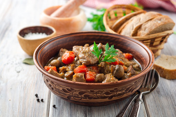 Turkey meat stew with mushrooms and vegetables in ceramic bowl on wooden table. Selective focus.