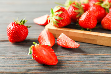 Cutting board and fresh strawberries on wooden table, closeup and space for text. Summer sweet fruits and berries