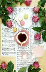 Canvas Print - Feminine desk or workspace coffee break time overhead flatlay with sheet music and roses.