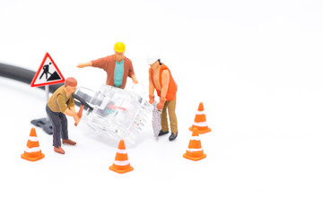 Macro shot on miniature figures as technicians working on the internet web network repair cable socket, isolated on white background. Information technology IT and business concept