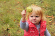 © hiddencatch - Adorable toddler girl with blond hair holding chestnut; autumn background