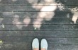 selfie shot of feet woman standing on wooden floor with shadow of bokeh from sunlight