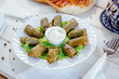 Dolma - rolls made from grape leaves and meat, on white plate.