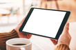 © Farknot Architect - Mockup image of a woman holding black tablet pc with blank white screen with coffee cup on wooden table