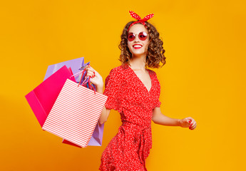 concept of shopping purchases and sales of happy young girl with packages  on yellow background.