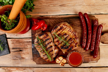 Wall Mural - Grilled meat. Steak pork grill on wooden cutting board  on  rustic background  Top view. Flat lay.