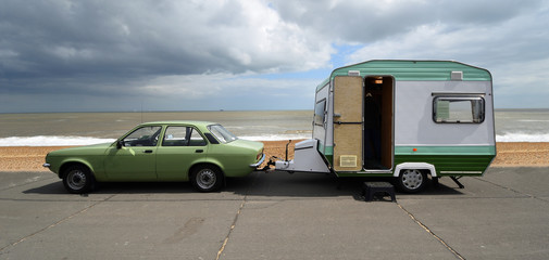 classic vauxhall chevette car towing small trailer - caravan on seafront promenade beach and sea in 