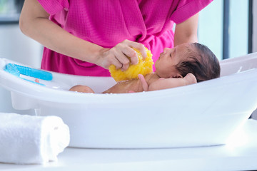 the mother cleaned the baby 2 months old, lying on the white cloth with the morning sun shining.