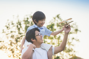 Asian father and son playing wooden airplane together