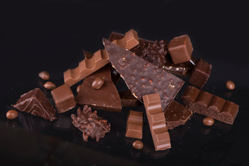 Sticker - Broken chocolate pieces and cocoa powder on wooden background.