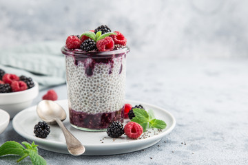 Healthy vegan chia seeds pudding with berry sauce and fresh raspberry and blackberry in glass