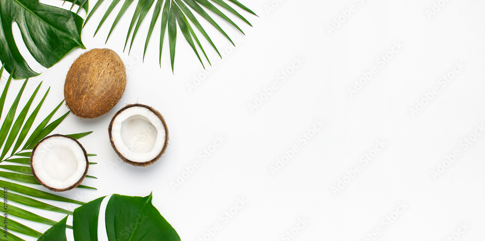Tropical leaves and fresh coconut on light gray background. Flat lay, top view, copy space. Summer background, nature. Healthy cooking. Creative healthy food concept, half of coconut - obrazy, fototapety, plakaty 
