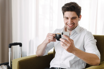 Poster - Handsome young businessman sitting in armchair in a hotel