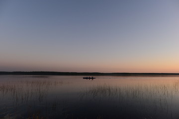 Wall Mural - Каyaking people  on the calm water of the lake in the sunset light return from a hike
