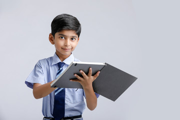 Wall Mural - Cute little Indian/Asian school boy showing note book over white background