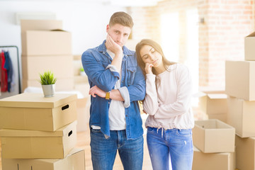 Poster - Beautiful young couple moving to a new house thinking looking tired and bored with depression problems with crossed arms.