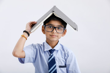 Wall Mural - cute little Indian / Asian school boy wearing spectacles with book on head