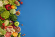 Healthy food dish on blue background. Healthful set including vegetables and fruits. Grape, apple, kiwi, pepper, lime, cabbage, zucchini, grapefruit, ginger, nuts. Proper nutrition or vegetarian menu.