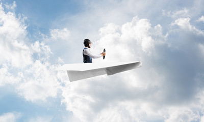 Businessman in aviator hat sitting in paper plane