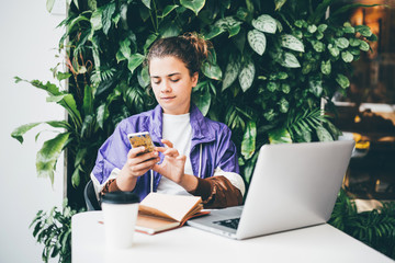 Young woman siting at co working, drinking coffee and working on laptop.