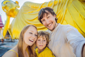 Happy tourists mother, father and son on background ofLying Buddha statue