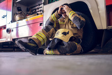 Image Of Young Tired Fireman Sitting On Floor Near Fire Truck