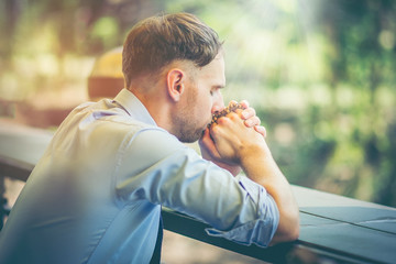 Wall Mural - Young male American bow front commemorate the teachings of Jesus. He holds the necklace of prayer beads in hand and praying from God.