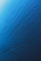textured aqua blue painted wall background and texture. the wall is illuminated with cyan light