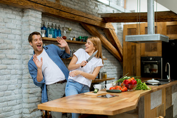 Wall Mural - Lovely cheerful couple cooking dinner together and having fun at rustic kitchen