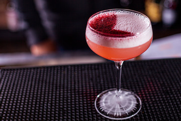 Cold pink strawberry cocktail in a glass. Restaurant serve, on a black background.