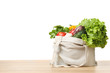 Cloth bag with vegetables on table against white background. Space for text