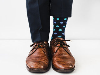 Office manager standing in stylish shoes, blue pants and bright, colorful socks on a white, isolated background. Close-up. Studio photo. Concept of lifestyle, fun and elegance