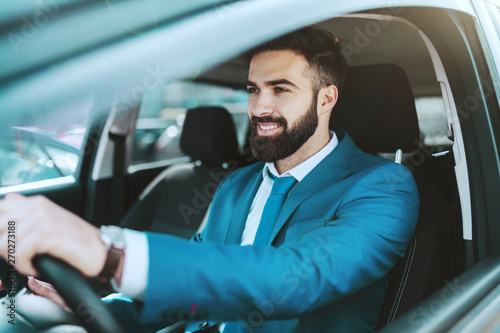 Young attractive prosperous Caucasian businessman in blue suit driving his car Poster Mural XXL