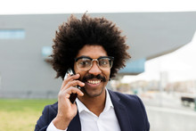 Portrait Of Smiling Businessman Talking On Smartphone Outdoors