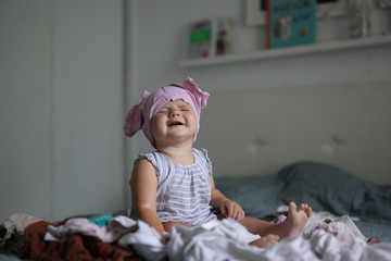 Funny Caucasian baby playing with bunch of clothes