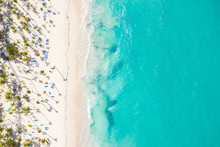 Aerial View From Drone On Caribbean Seashore With Coconut Palm Trees And Sunbeds. Summer Holidays