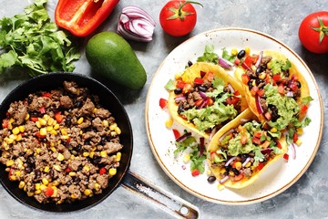 Sticker - Mexican tacos with fried minced meat with corn and black beans, onions, fresh tomatoes and cilantro are flavored with guacamole sauce. top view.