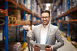 Portrait of successful middle aged caucasian manager businessman holding tablet computer in large warehouse organizing distribution. Business people.