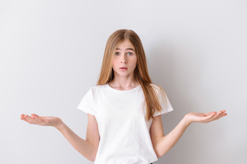 Wall Mural - Confused teenage girl on light background