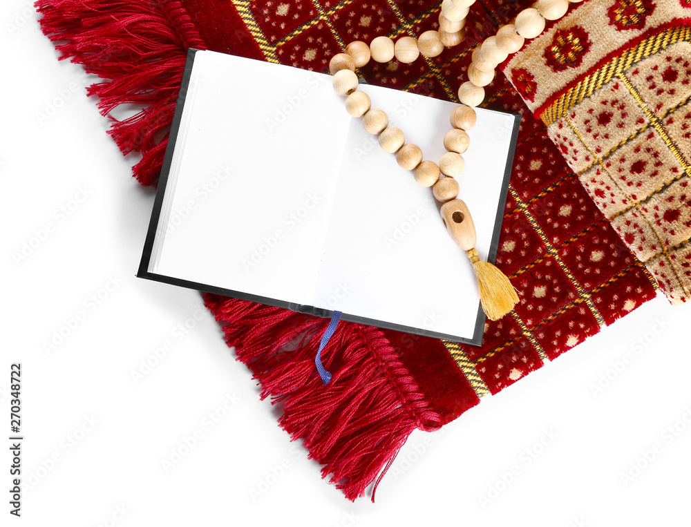Muslim prayer mat, beads and Koran on white background