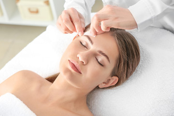 Wall Mural - Young woman undergoing eyebrows epilation in beauty salon