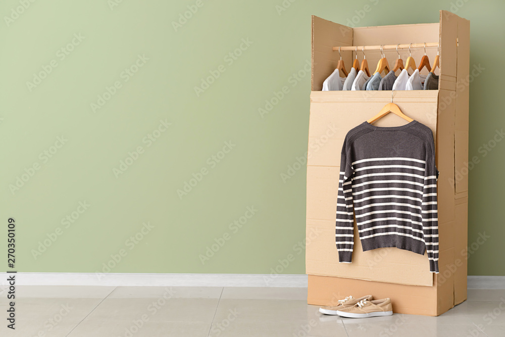 Wardrobe box with clothes near color wall