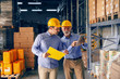 © Dusan Petkovic - Two business partners in formal wear and with protective yellow helmets on heads standing in warehouse and comparing data. Younger holding folder while older one pointing at calculations on tablet.
