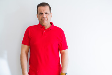 Middle age man wearing red t-shirt over white wall depressed and worry for distress, crying angry and afraid. Sad expression.